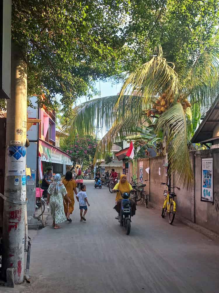 La via principale dell'isola di Gili Air con gente che cammina, bici e scooter elettrici